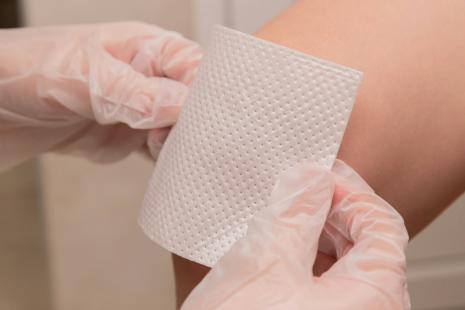 pose de pansement sur un genou, mains de soignant