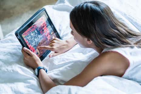 Fillette de 12 ans jouant sur une tablette numérique.