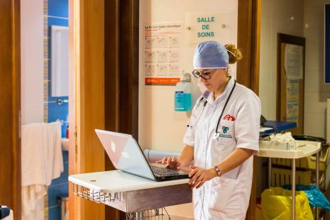 Infirmière dans un couloir d'hôpital, consulte un ordinateur