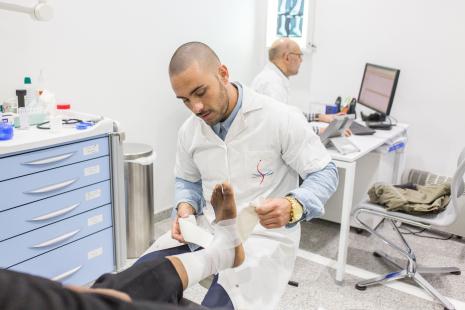 Infirmier posant un strapping sur une cheville pour traiter une entorse