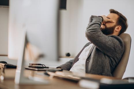Homme au bureau se frottant les yeux